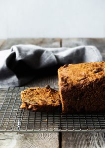 rosemary bread on a cooling rack with a slice cut off and a linen towel in the background.