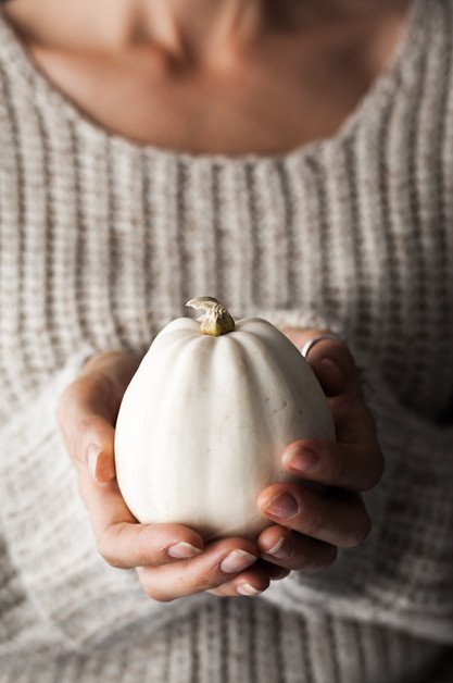 woman holding a white mini pumpkin. 