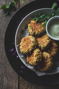 overhead view of a plate of falafels and dip on a wood surface.