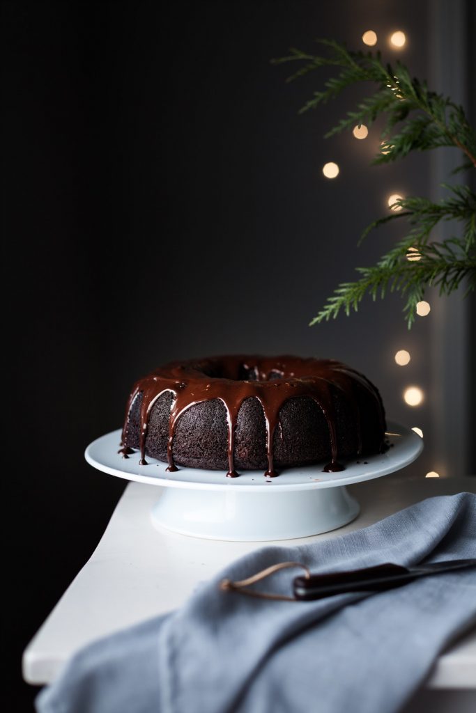 a head on image of chocolate bundt cake with twinkle lights in the background.