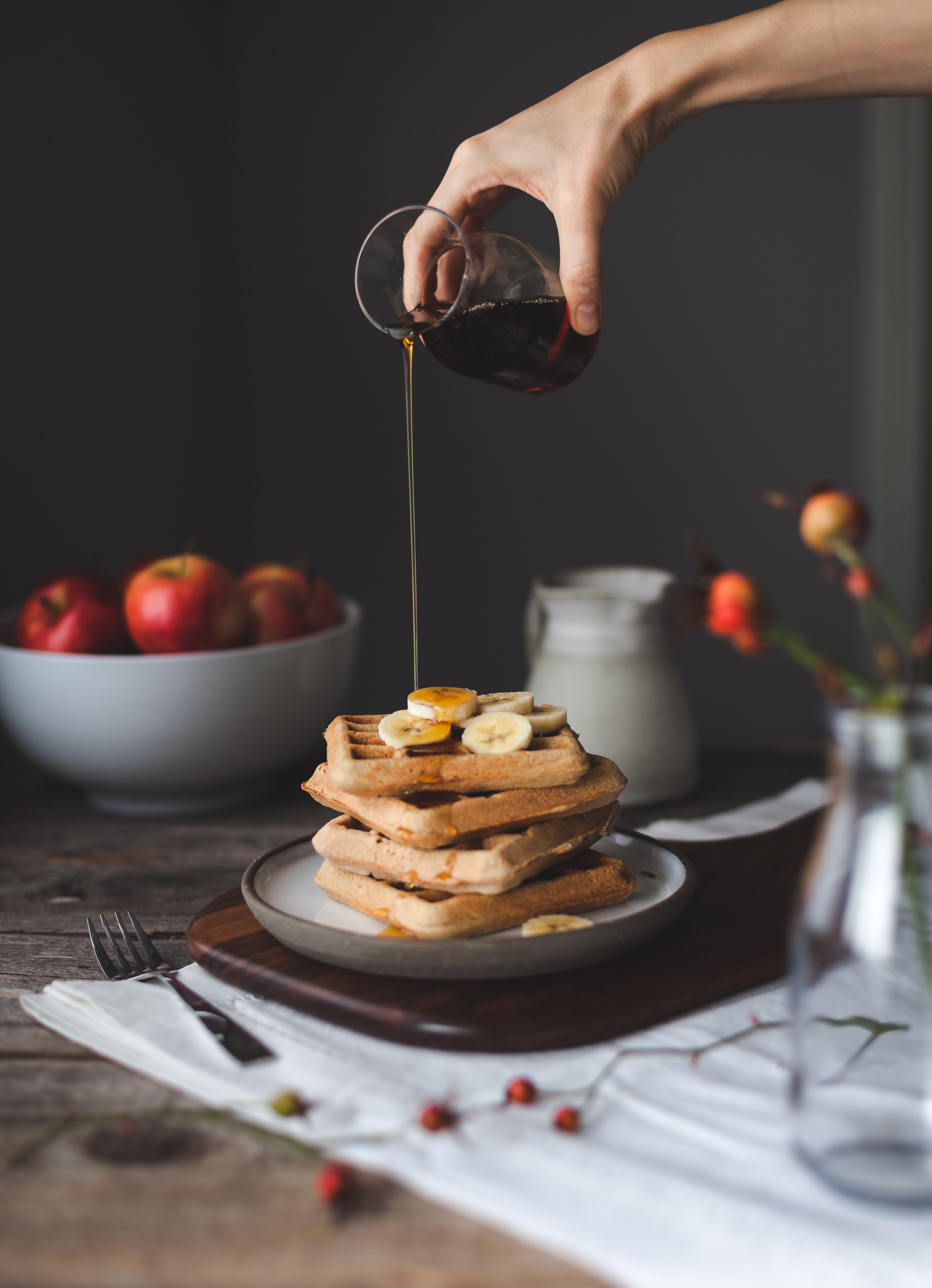 a stack of waffles on a plate with maple syrup being drizzled on top.