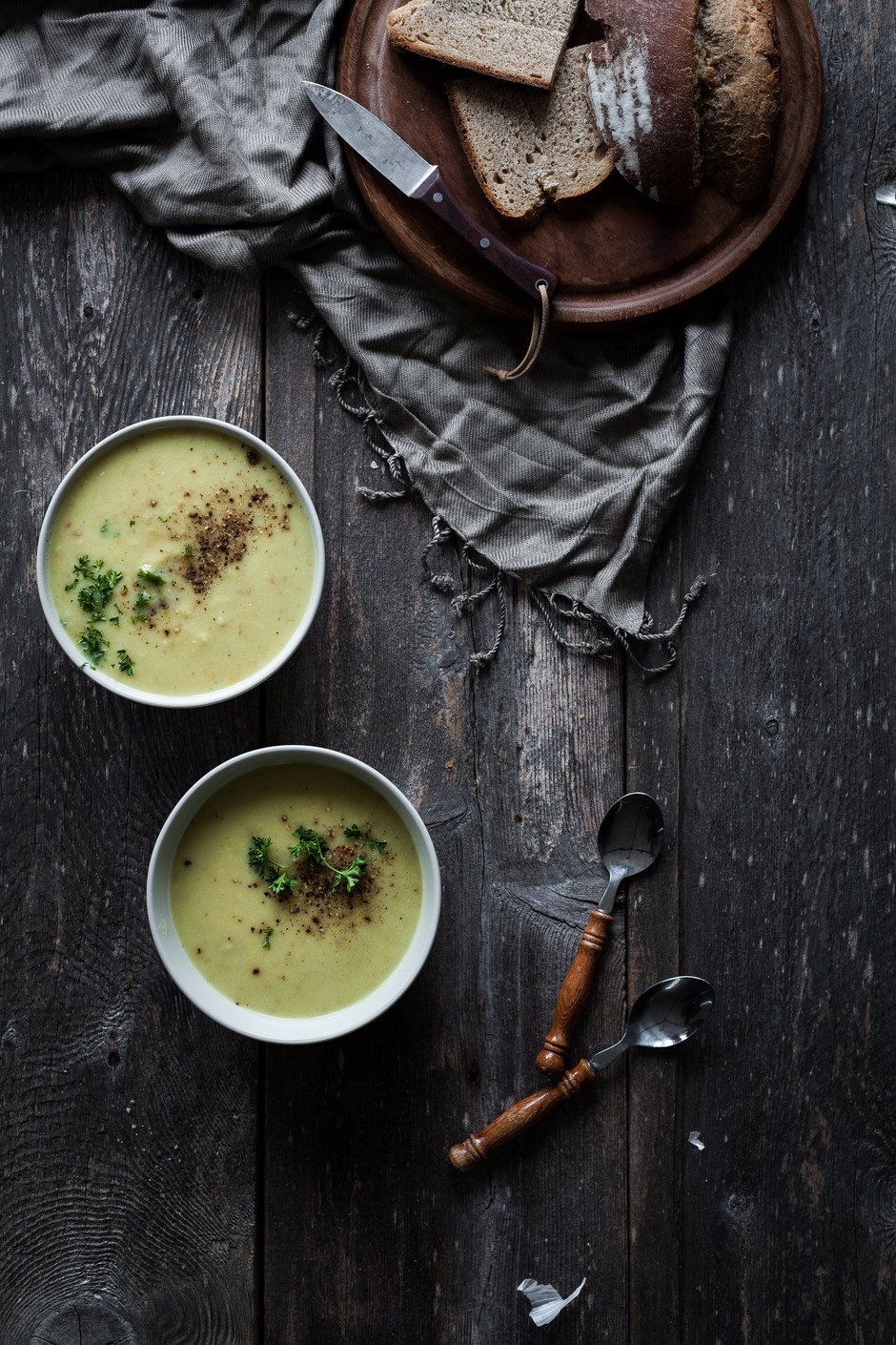overhead view of two bowls of potato leek soup with bread.