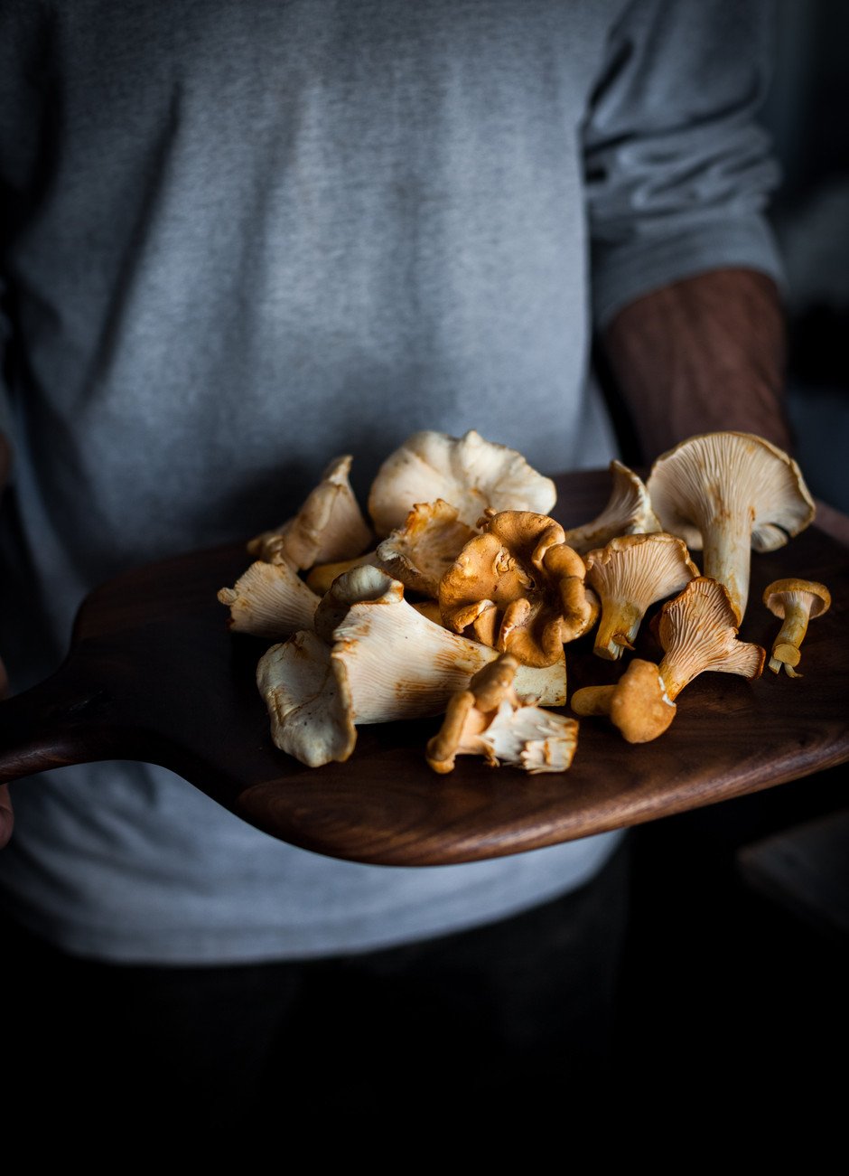 a person holding a cutting board with chanterelles.