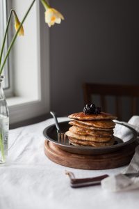 a head on image of a stack of multigrain pancakes sitting next to a window.