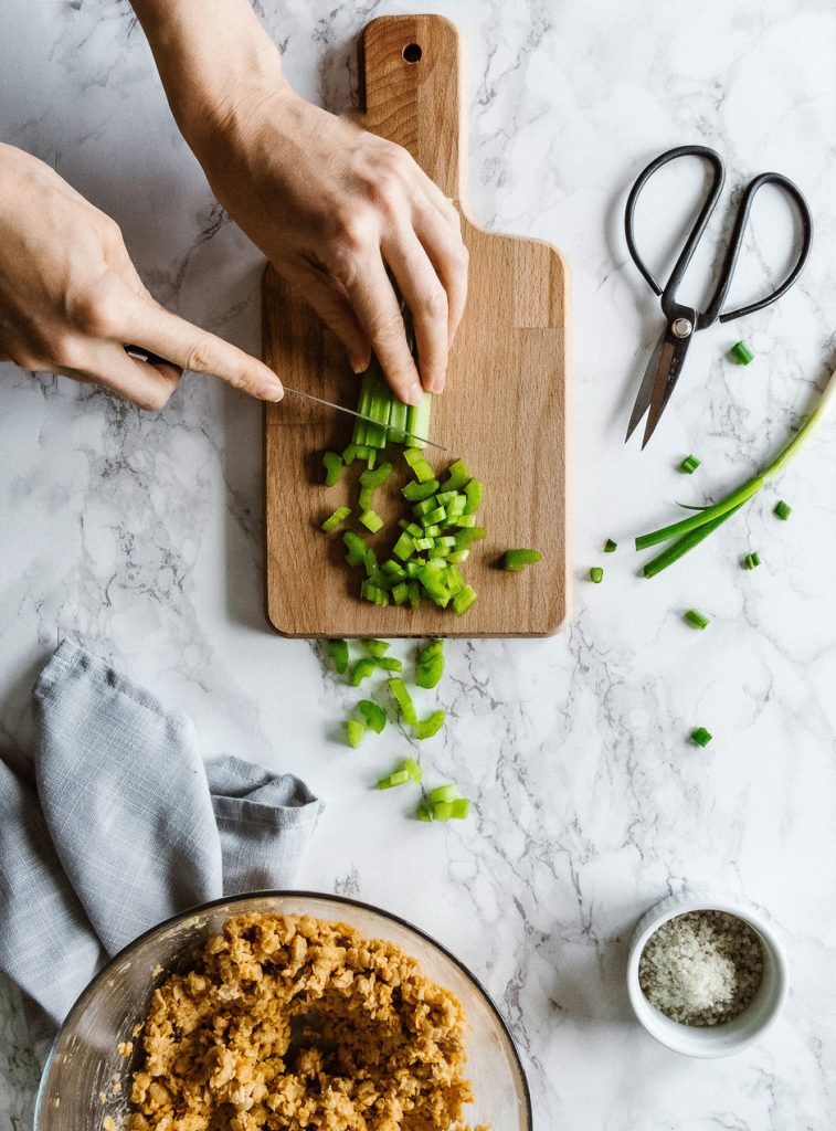 a cook chopping herbs on a cutting board.