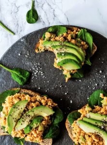 overhead of three chickpea sandwhcihes on a slate board with spinach and salt.