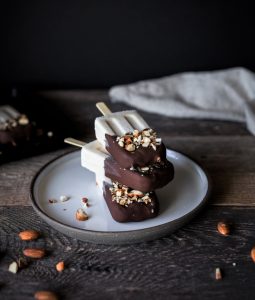a stack of three ice cream bars on a white plate with a linen in the background.