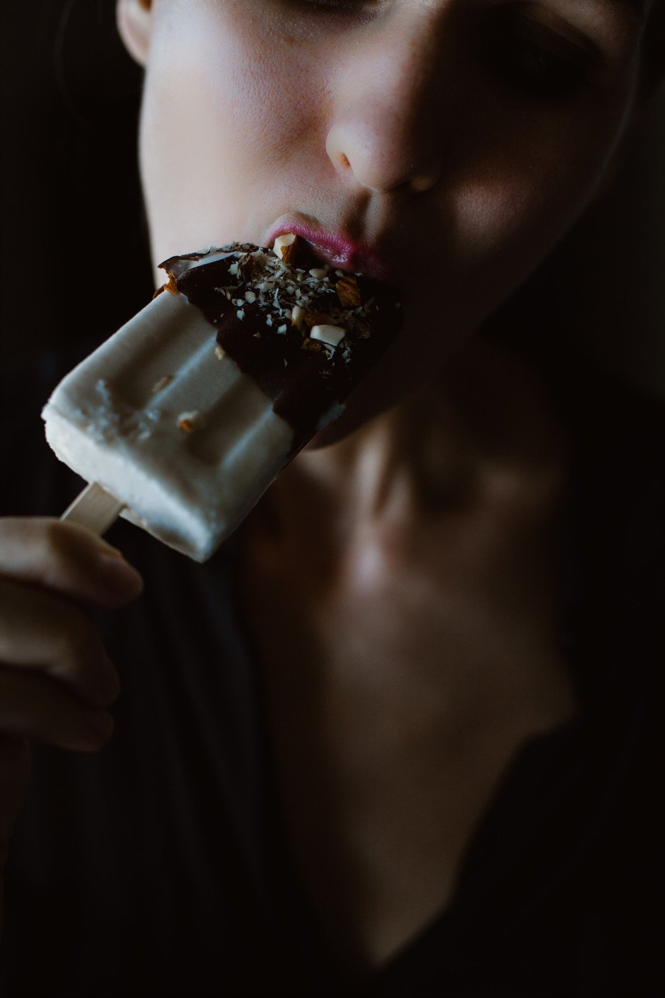 closeup portrait of a person eating an ice cream bar.