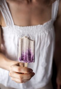 a person holding a creamsicle with two bites missing.