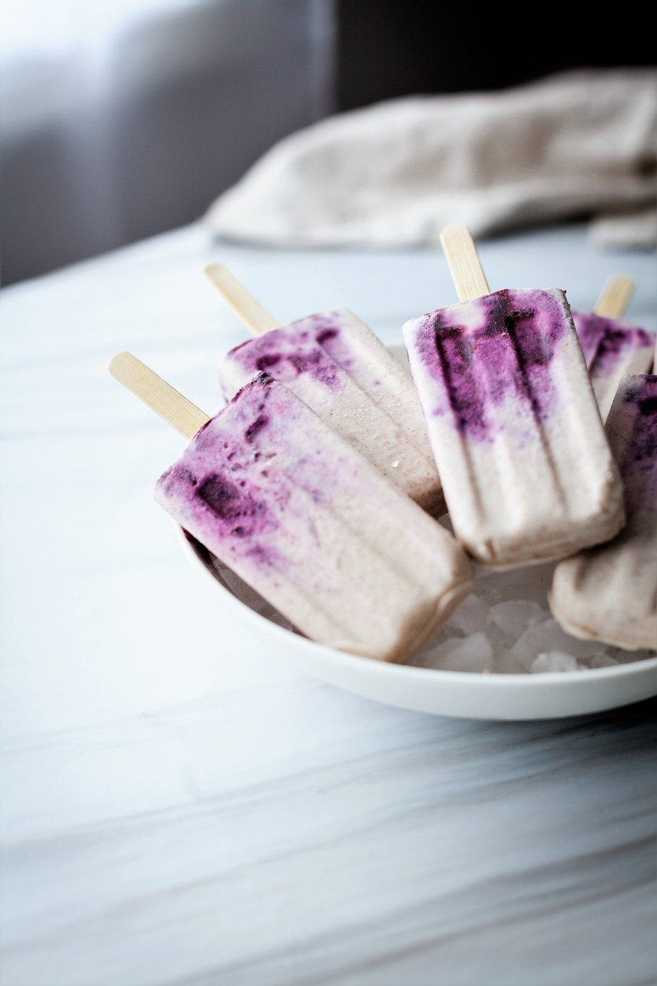 head on image of blueberry chai creamsicles sitting on a bowl of ice. 