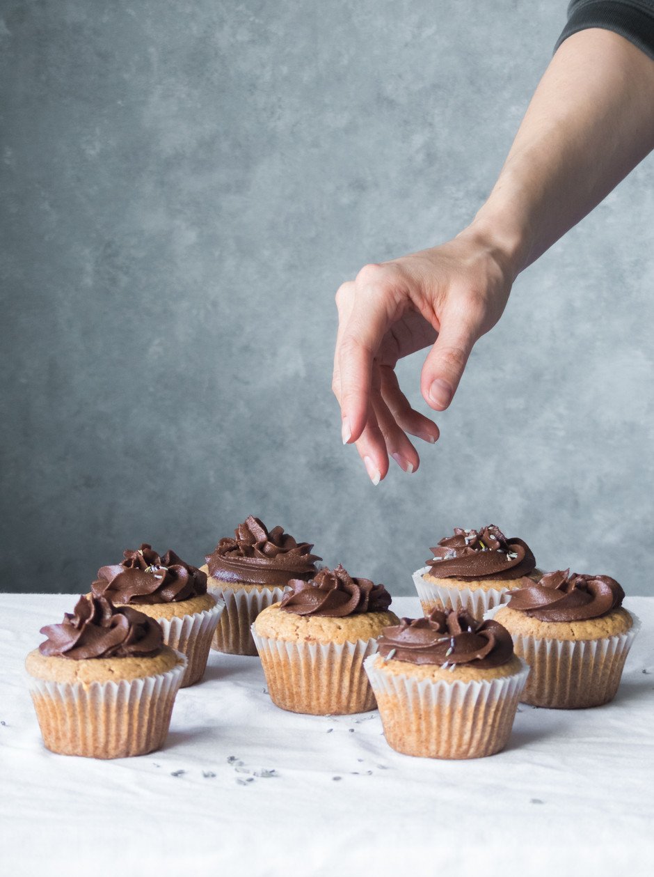 a hand reaching for a cupcake. 