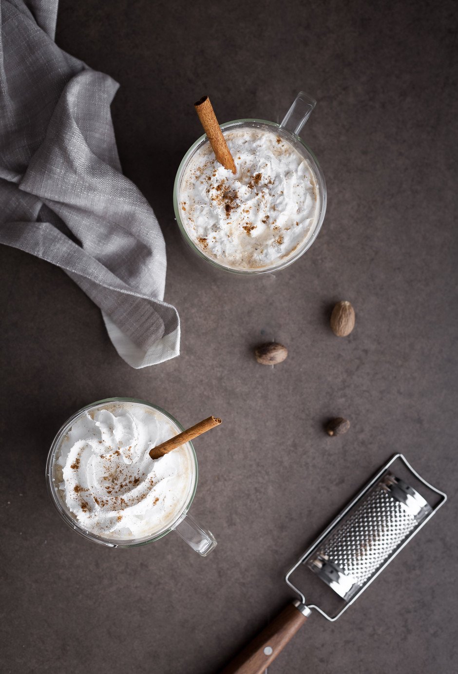 overhead image of two lattes sitting on a grey background with a blue linen napkin.