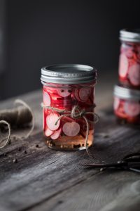 a head on image of a jar of pickled radishes with a twine bow.