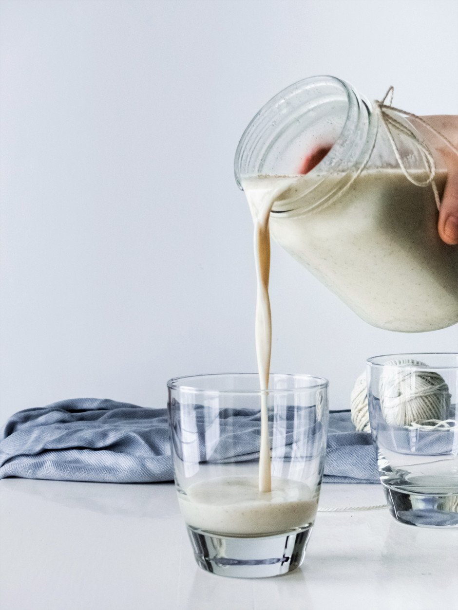 a head on image of vegan egg nog being poured out of a mason jar.