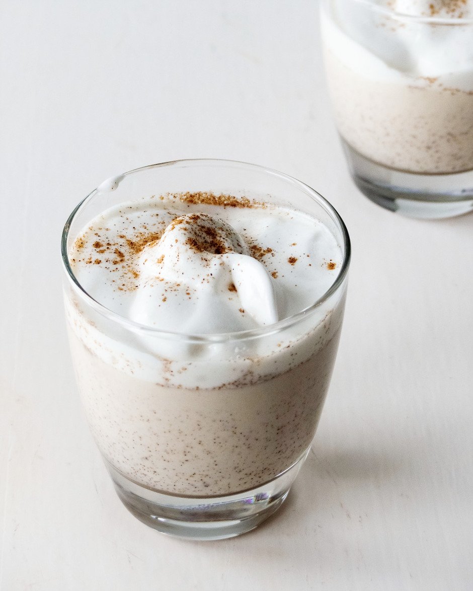 a ¾ angle image of homemade vegan eggnog in a glass with vegan meringue on top.