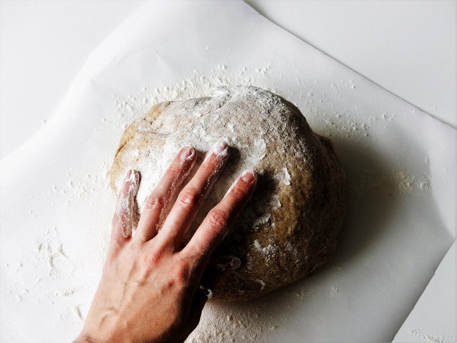 overhead image of persons hand ontop of a dough ball.