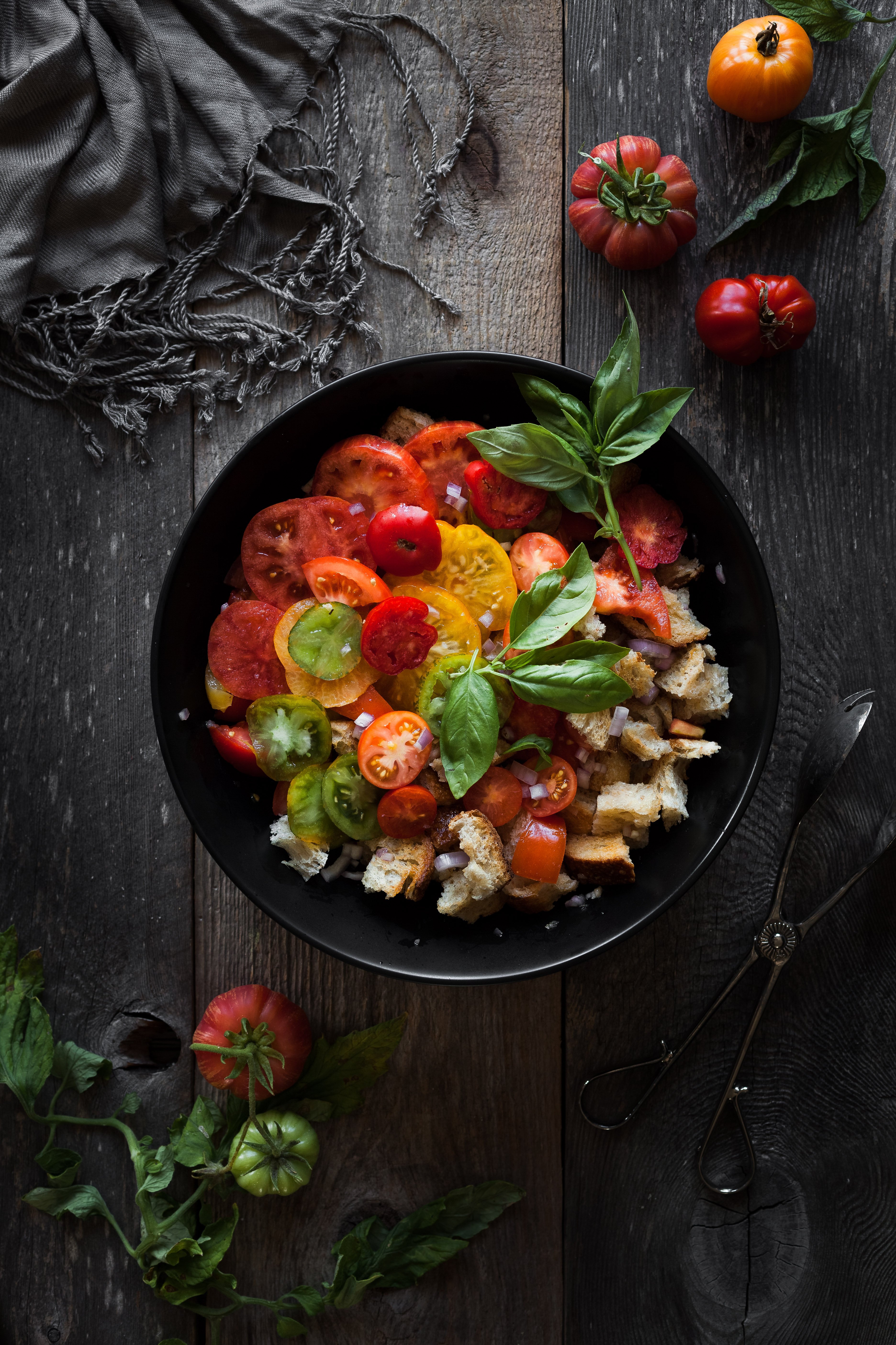 an overhead image of a bowl of panzanella with fresh tomatoes off to the side.