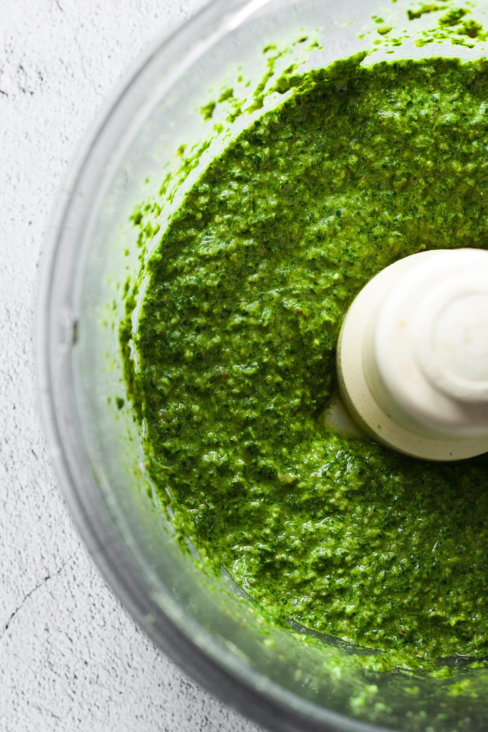 overhead closeup of pesto in a food processor bowl.