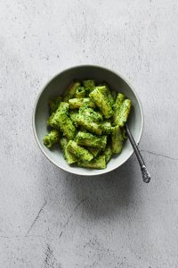 a overhead shot of a bowl of Rigatoni with pesto with a fork.