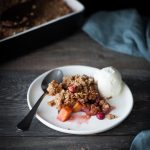 Cranberry Persimmon Crisp on a white plate with a scoop of ice cream.