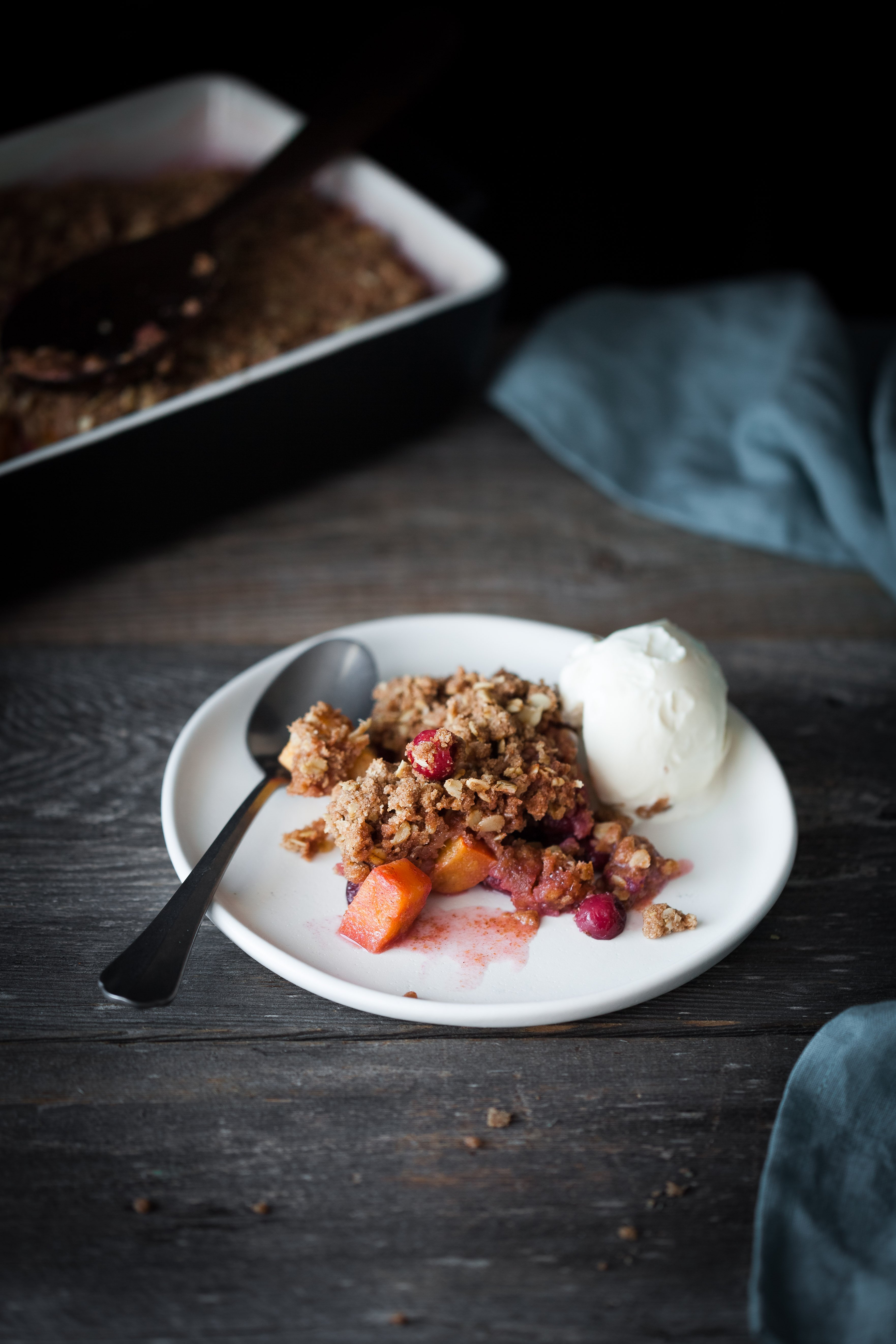 Cranberry Persimmon Crisp on a white plate with a scoop of ice cream.