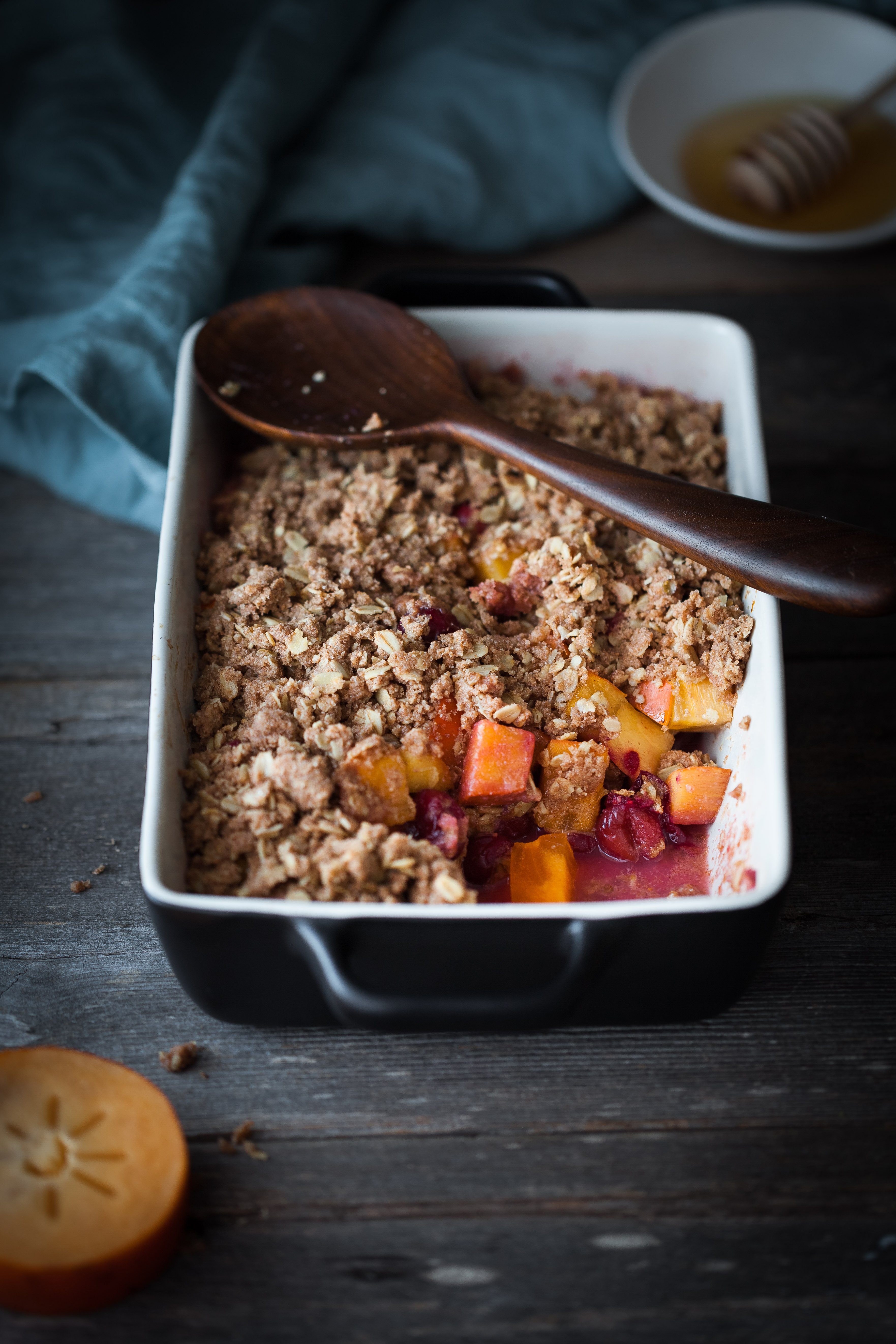 cranberry crisp in a back baking dish with a scoop out of it.