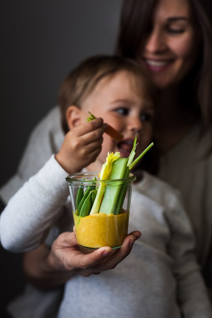 Mother and son smiling enjoying a snack jar with gold dip from Little Green Kitchen.