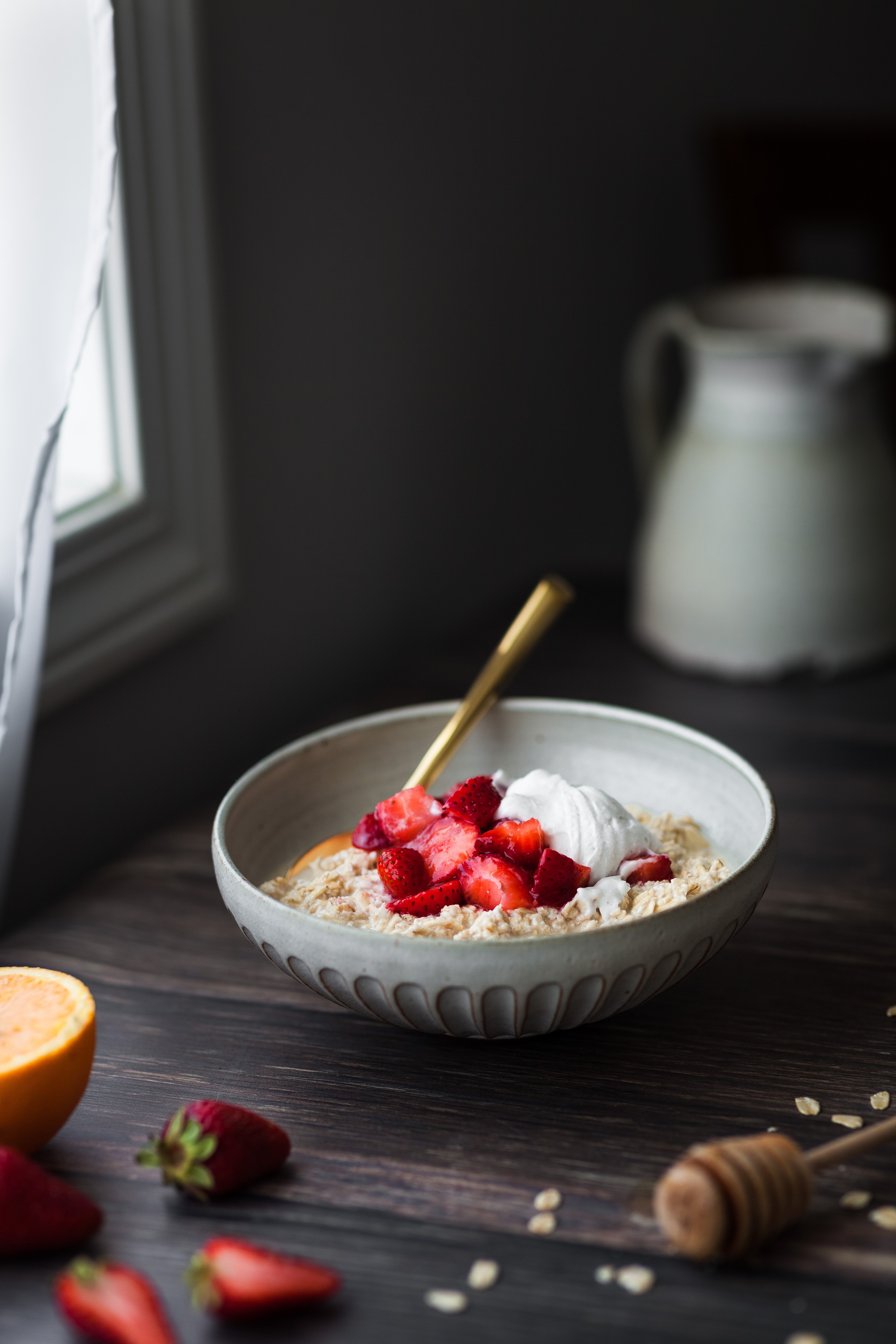 head on image of a bowl of vegan strawberries and cream bircher museli sitting by a window.
