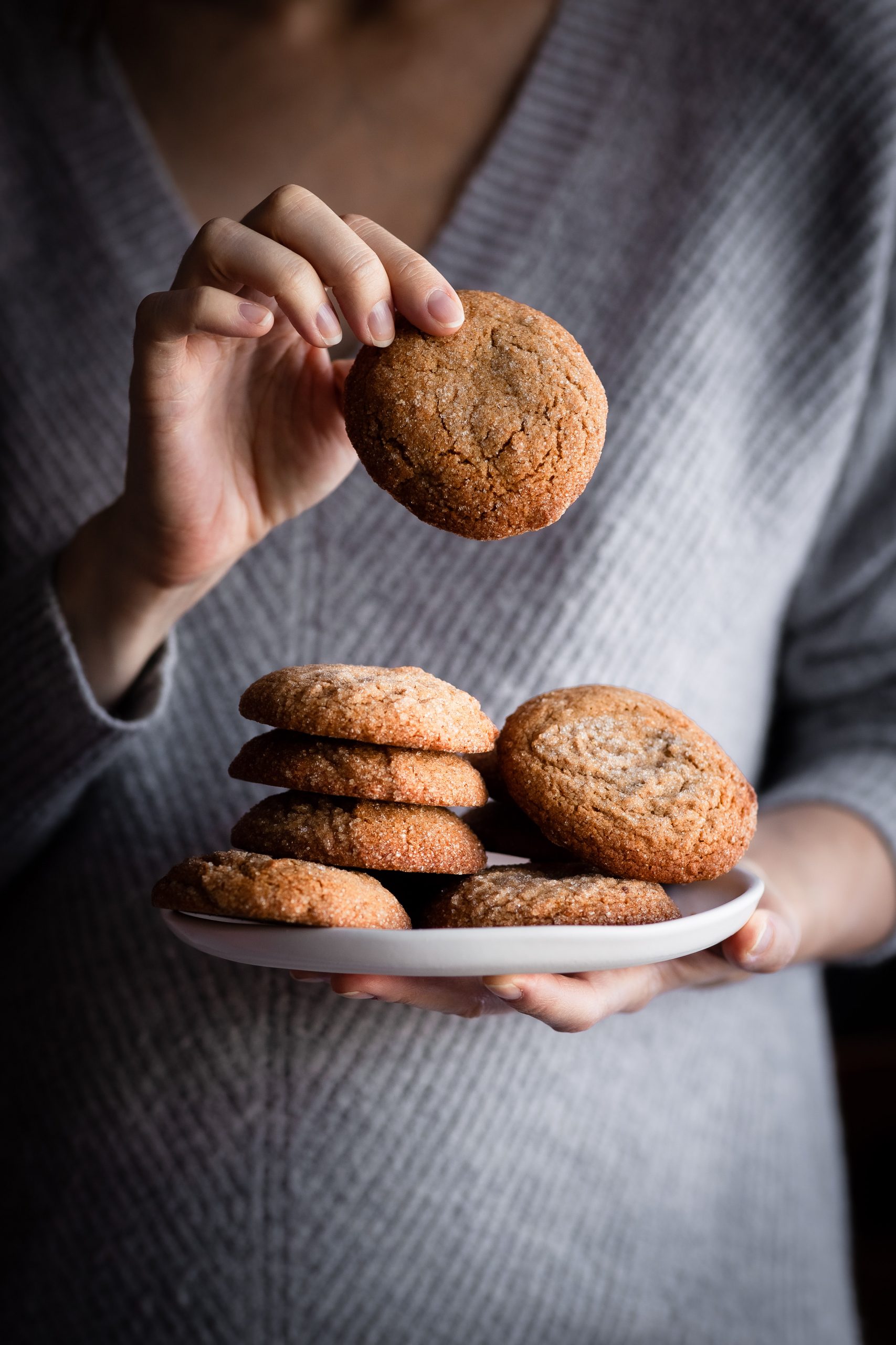 a person holding a plate of vegan ginger spice cookies.