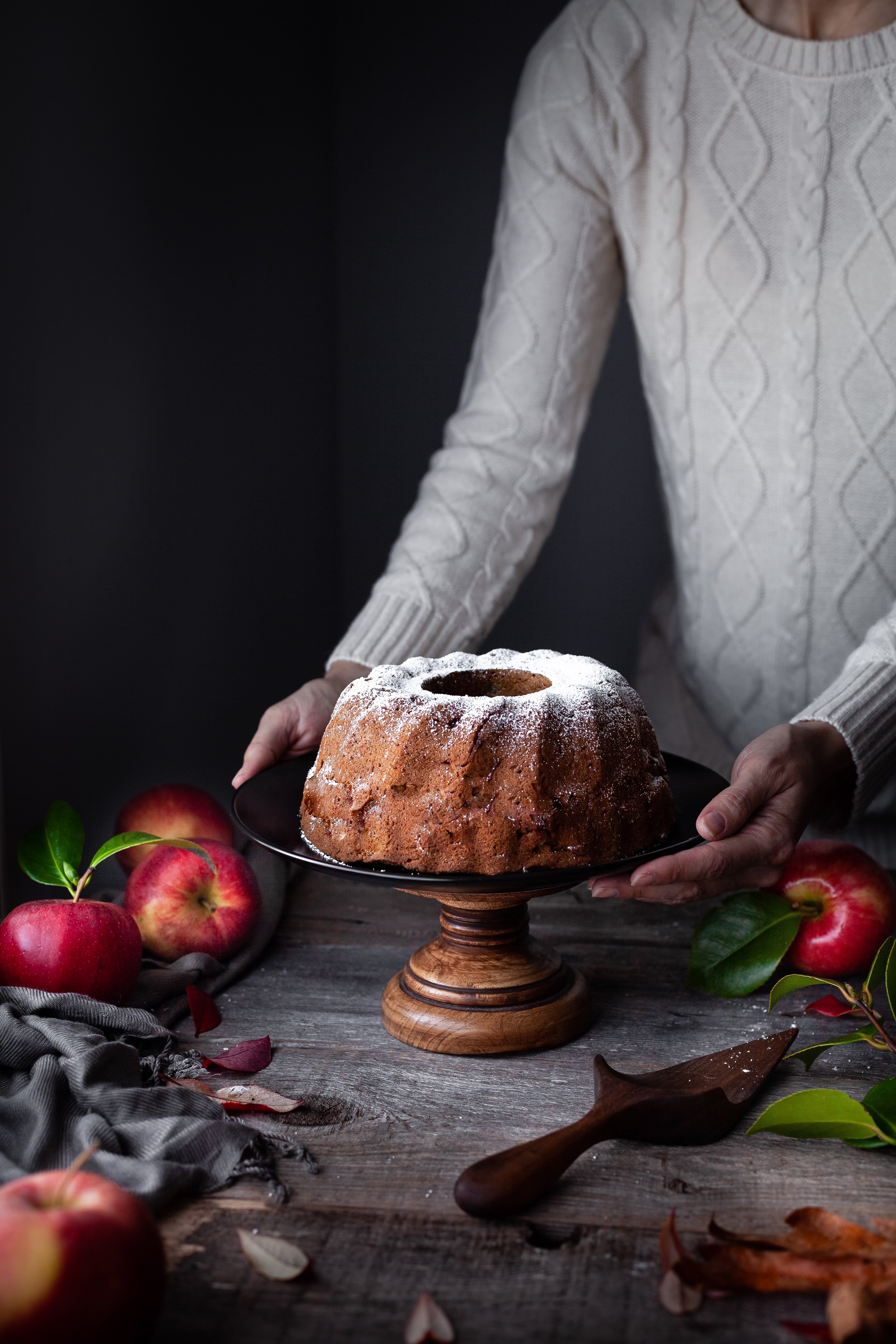 head on image of vegan apple spice cake with bakers hands.