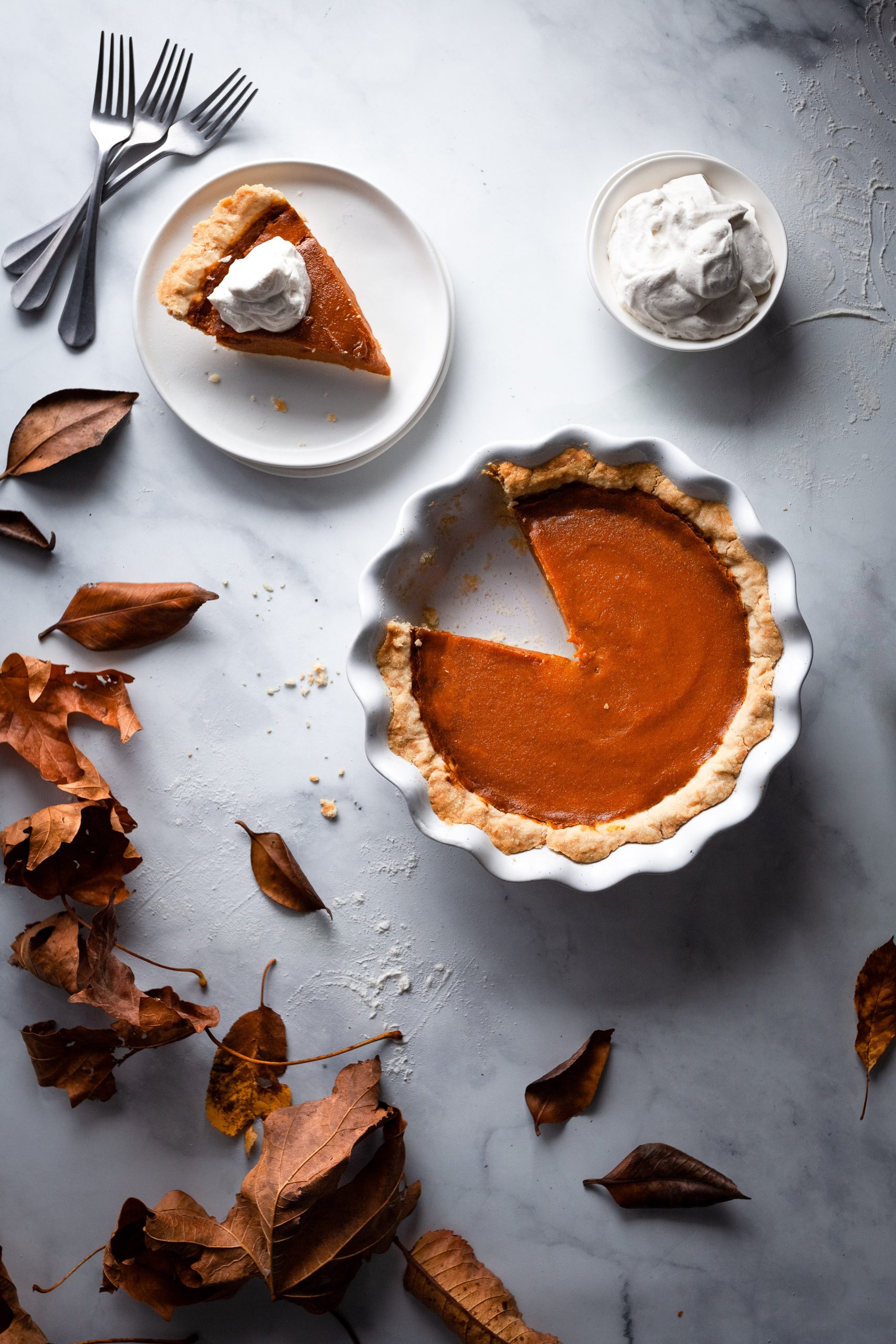 overhead image of vegan pumpkin pie with a slice on a plate.