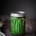 A jar of pickled green beans with twine bow around it.