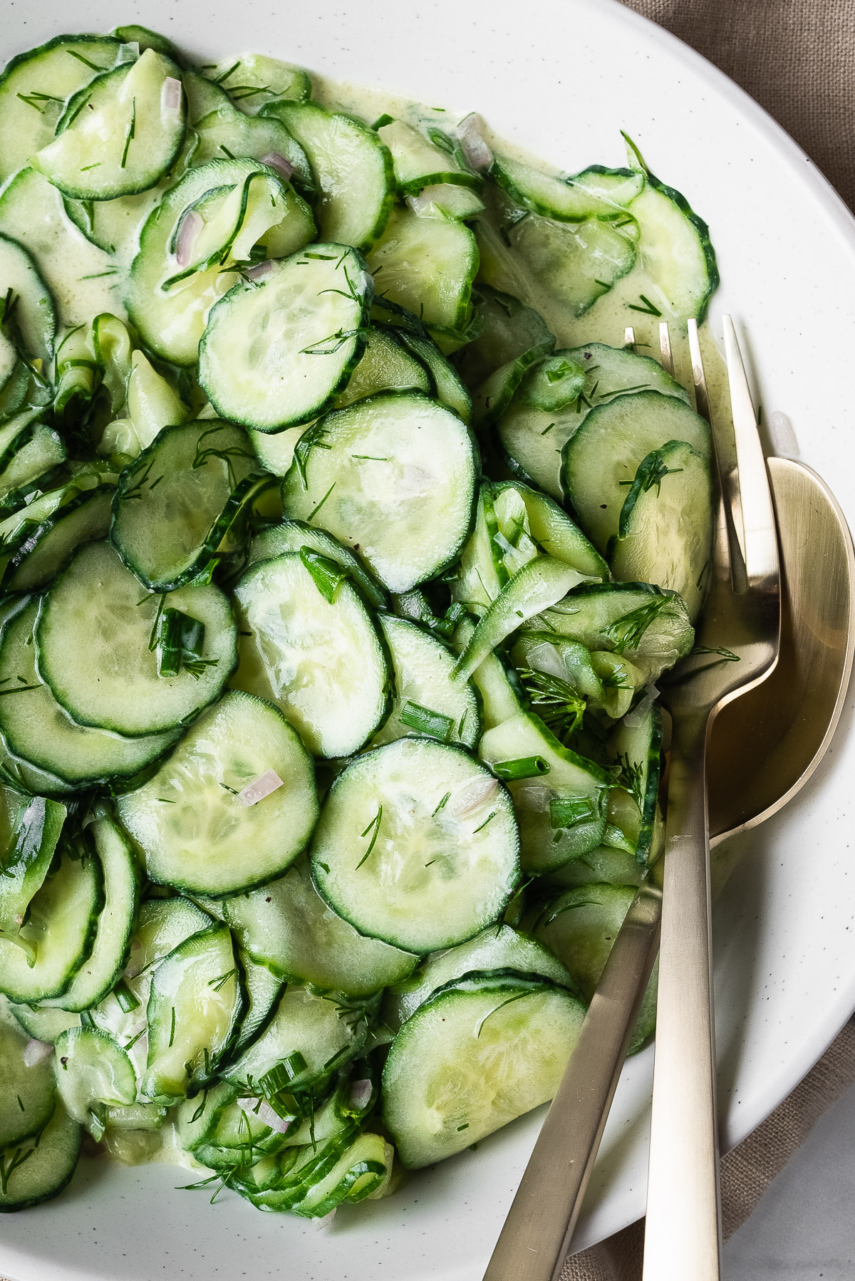 Closeup view of sliced cucumbers in dressing.