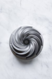A stainless steel bundt pan on a marble surface.