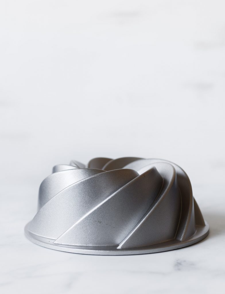 Portrait view of a stainless steel bundt pan on a marble surface.