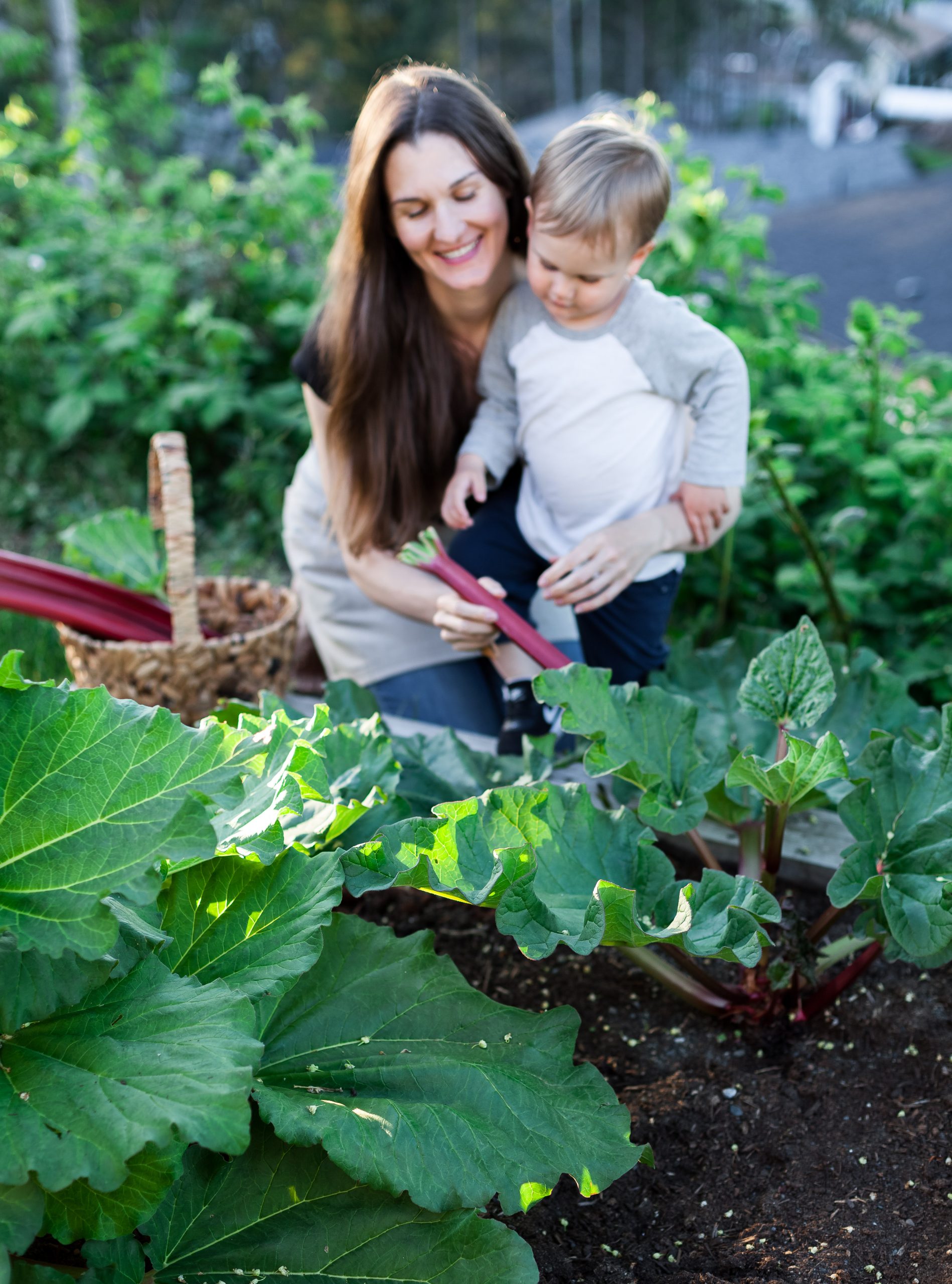 a mother and small child in a rhubarb patch.
