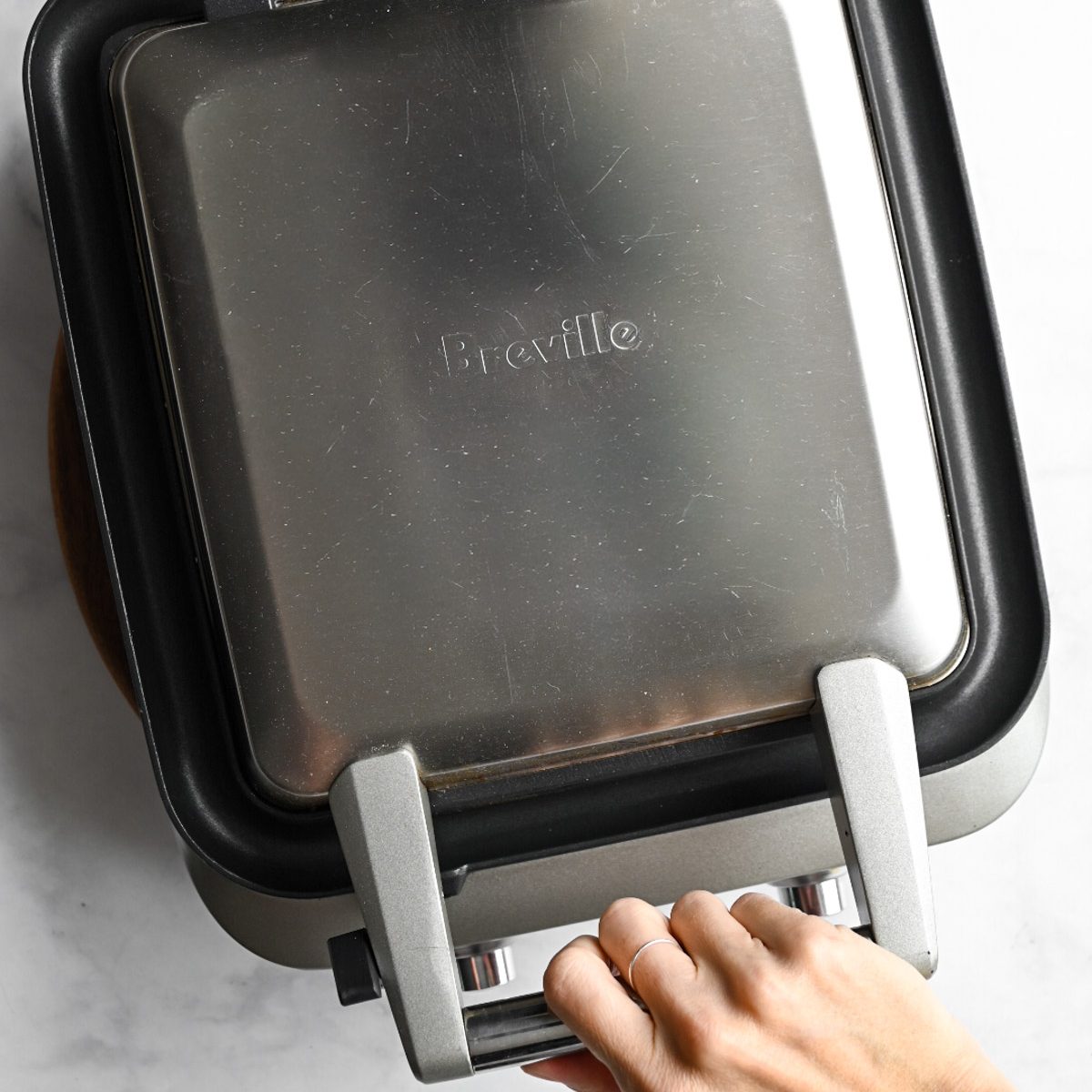 a closed waffle iron making waffles on a marble surface.