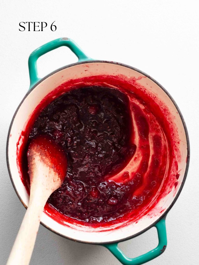 finished cranberry sauce in a blue pot with a wooden spoon on a white surface with text overlay "step 6".