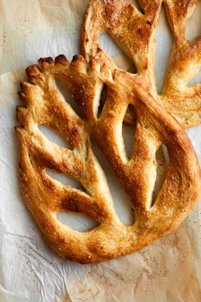 two fougasse breads which are shaped like a leaf with holes in the middle that resemble leaf veins.