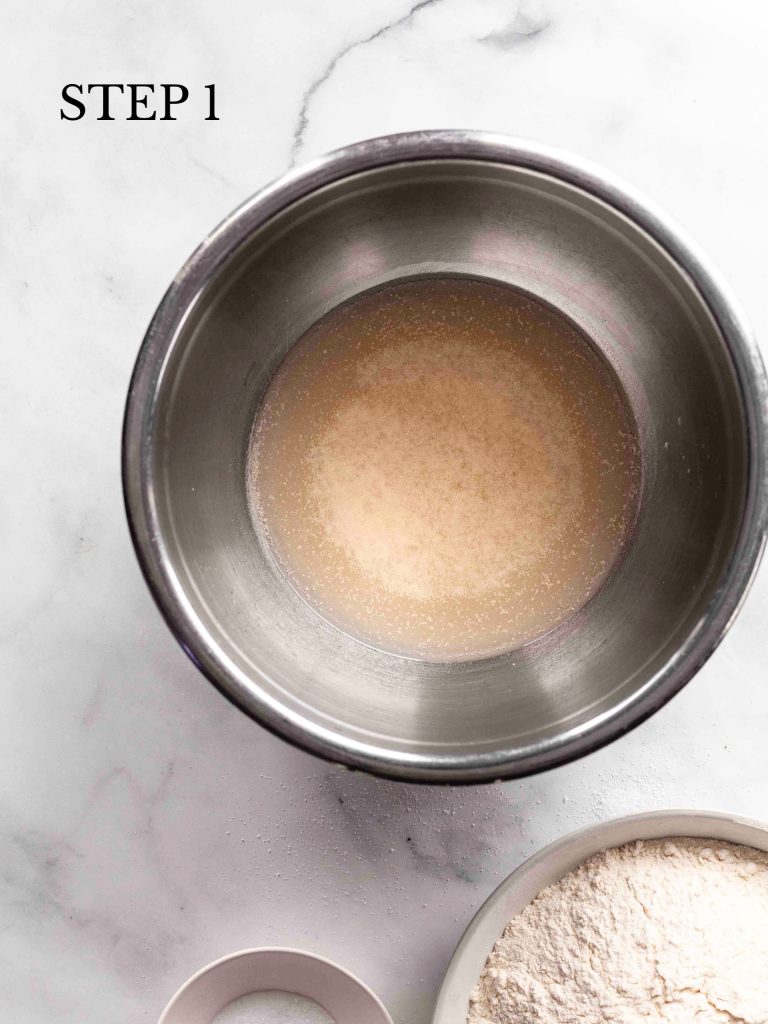 bubbly yeast and water in a stainless bowl on a white surface with text overlay "Step 1".