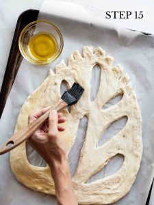 a baker brushing olive oil onto dough with text overlay "step 15".