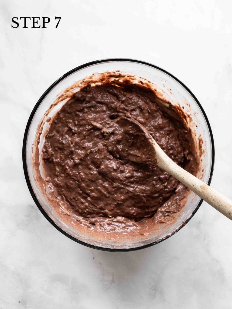 mixed batter on a white marble surface with a wooden spoon.